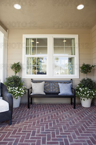 Covered porch with brick flooring and bench