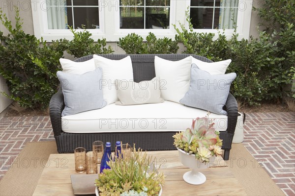 Wicker couch with cushions on brick flooring at a patio