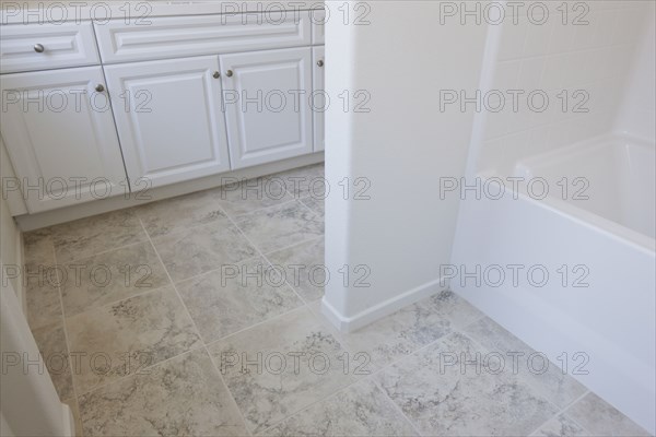 High angle view of cropped white cabinets and tiled floor at home