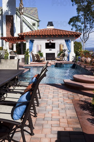 Chairs at cropped table with swimming pool in the background