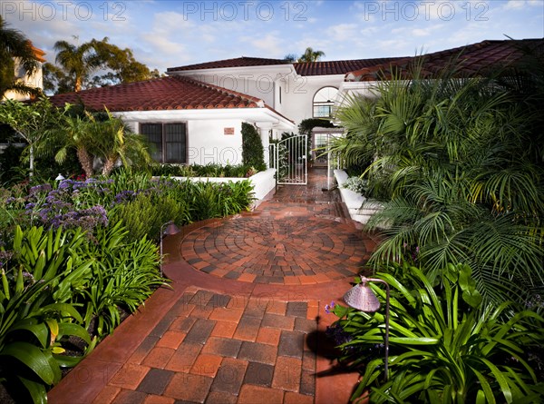 Brick walkway along plants leading to open gate at Laguna Niguel