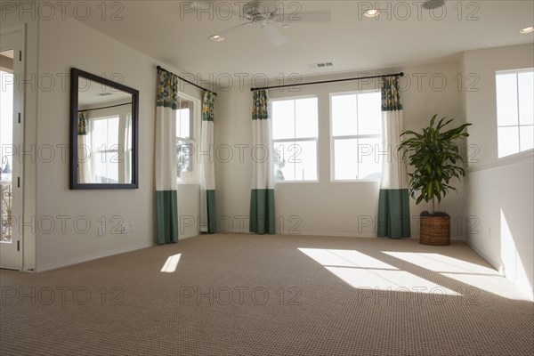 Empty room with carpet on floor and curtains on windows at home