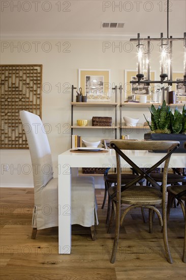 Chairs at dining table with shelves in the background at home