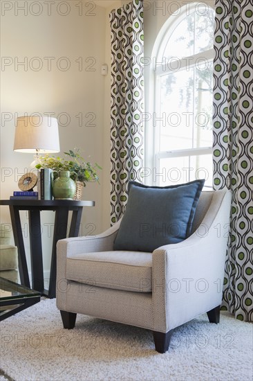 Upholstered armchair with end table by the window at home