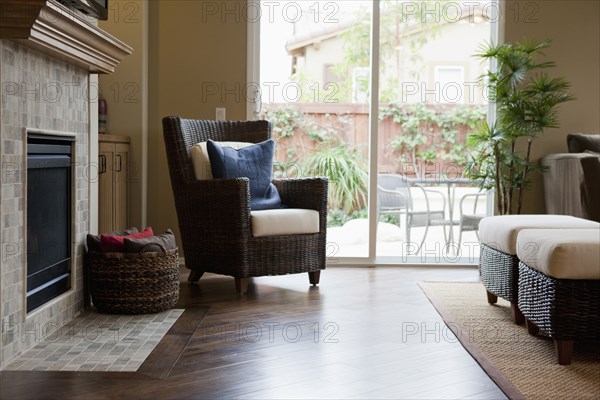 Wicker armchair and basket by mantelpiece in living room