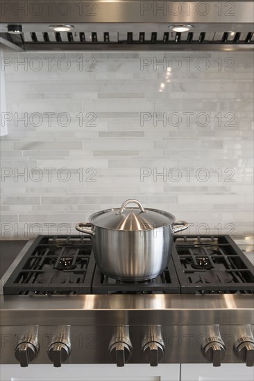 Sauce pan on stove against backsplash in kitchen