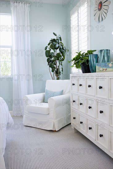 Arm chair by drawers in bedroom