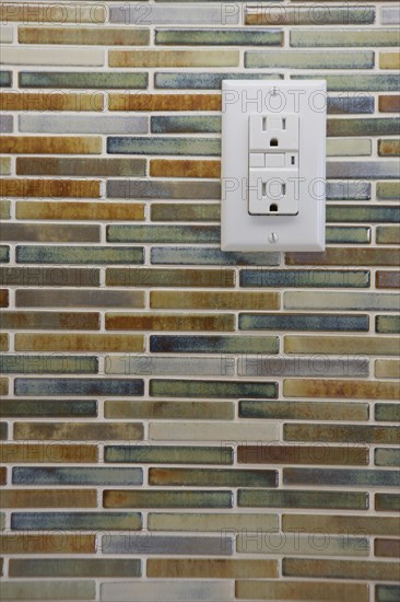 Close-up of tile backsplash with electrical socket