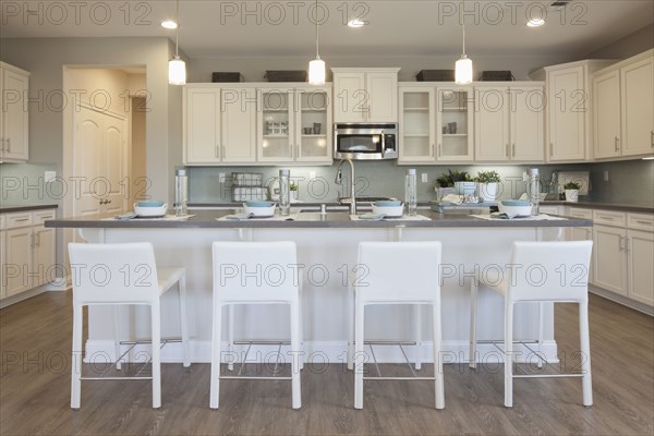 White bar stools at breakfast bar in domestic kitchen