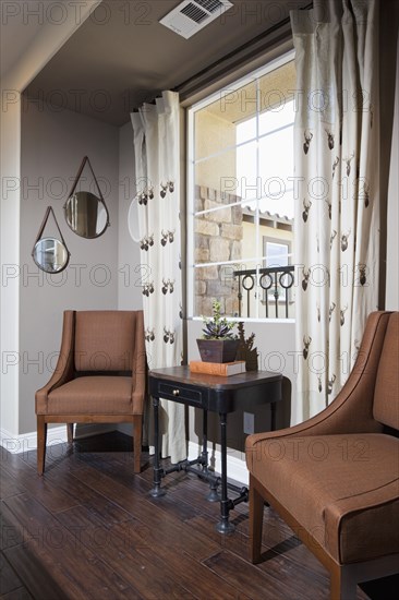 Brown chairs and end table against window
