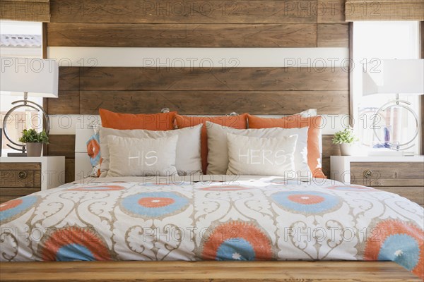 Cozy and tidy bed with wood paneled wall in contemporary bedroom