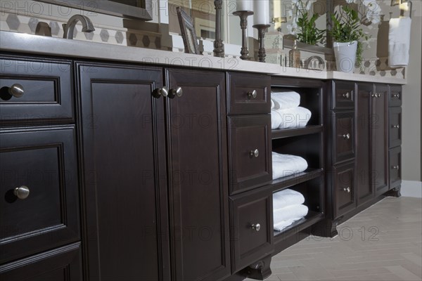 View of clean towels in brown cabinets with candle holders on counter at home