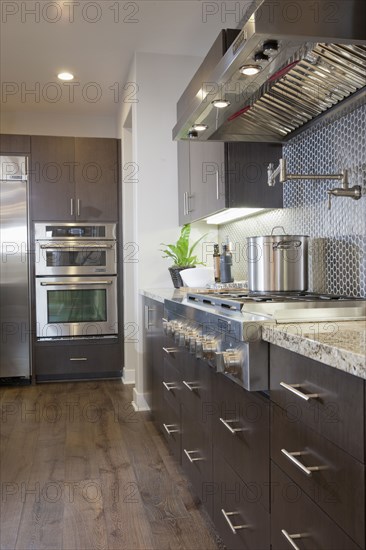 Kitchen having brown cabinets with vent hood at home