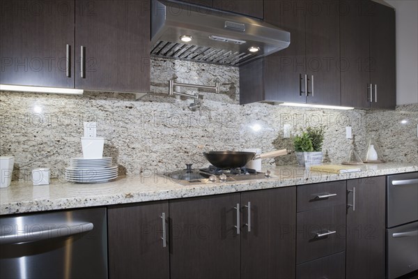 Kitchen having brown cabinets with granite counter top and wall at home