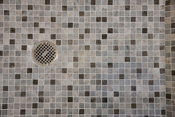 Close-up of drain in mosaic tile floor in the bathroom at home