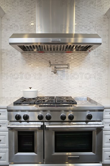 Kitchen with double oven gas stove below vent hood at home