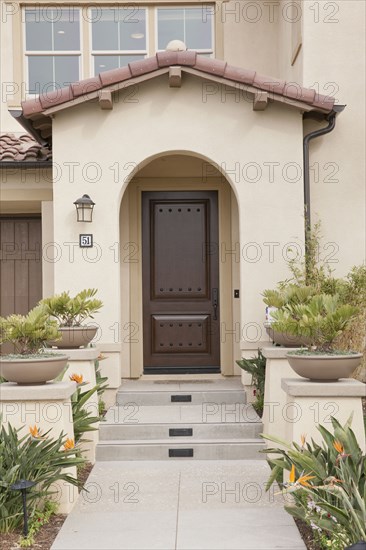 Walkway leading to a house with closed brown door at Irvine