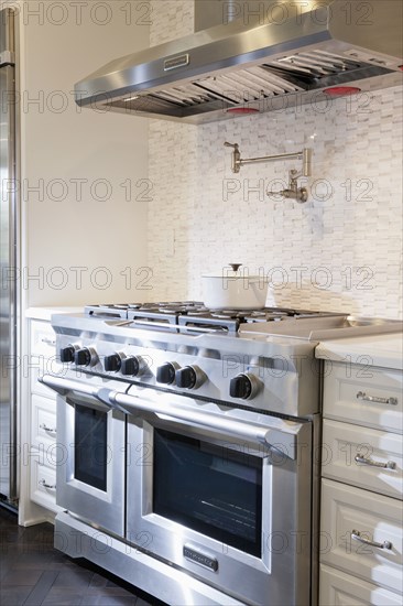 Kitchen with double oven gas stove below vent hood at home