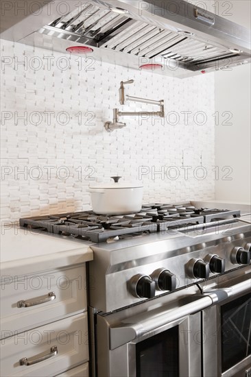 Kitchen with double oven gas stove below vent hood at home