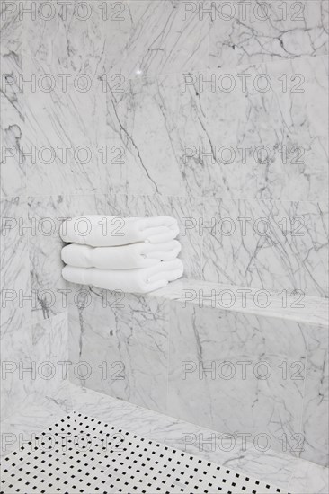 Folded white towels on marble seat in the bathroom at home