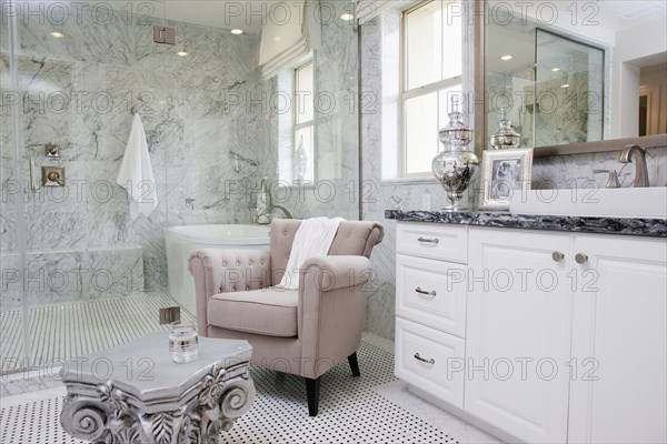 Sitting area with bathtub across the glass wall in the bathroom