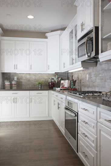 Kitchen having white cabinets and wooden floor at home