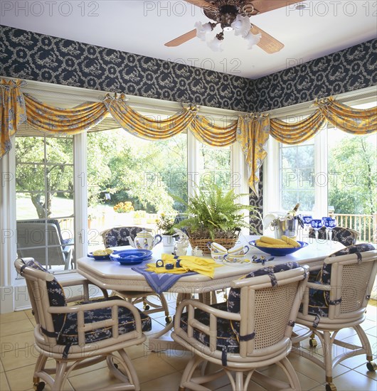 Dining table and chairs arranged in sunroom of traditional home