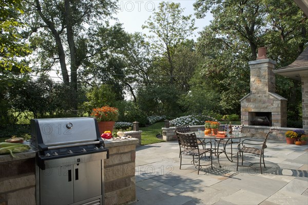 Outdoor seating furniture with stove and fireplace at patio of home.