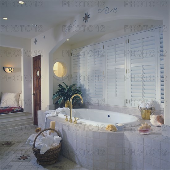 Tub with tile surround set in arched alcove with shuttered windows