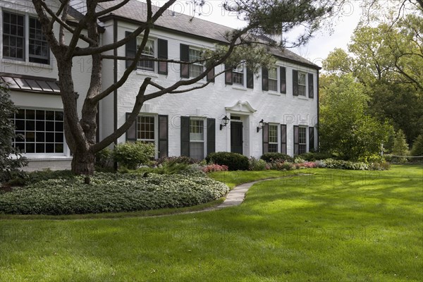 White brick traditional colonial home with black shutters