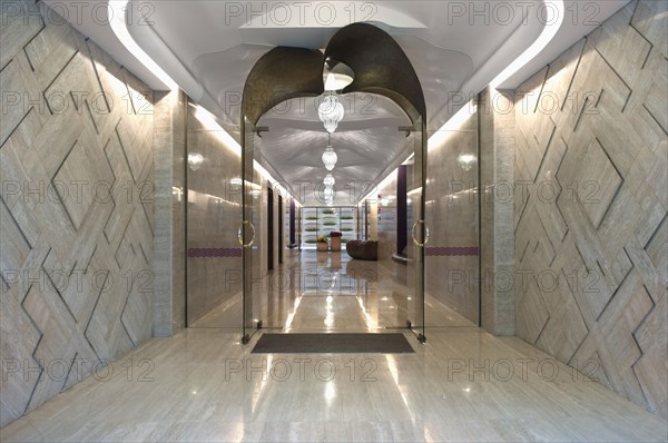 Long marble hallway with double glass doors at end