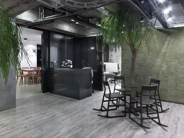 Modern circular table with tree in center in industrial office building