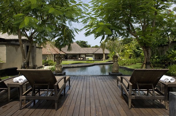 Two wicker lounge chairs on deck near pool