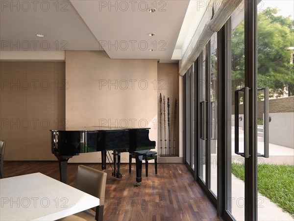 Baby grand piano in corner near double glass doors