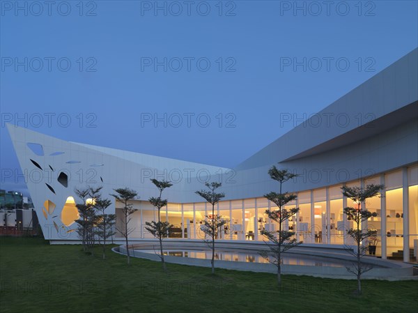 Row of trees and reflecting pool out front of modern building