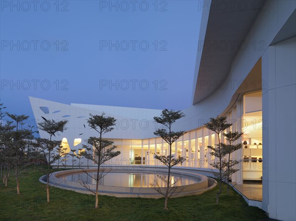 Row of trees and reflecting pool out front of modern building