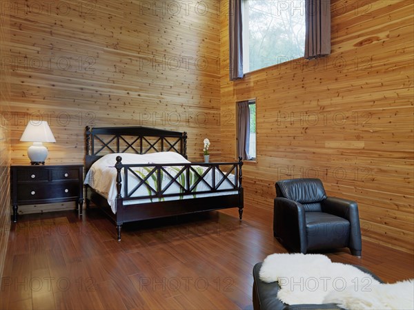 Master bedroom with black leather chair in cabin home