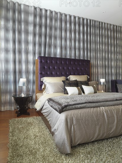 Elegant modern bedroom with purple velvet headboard