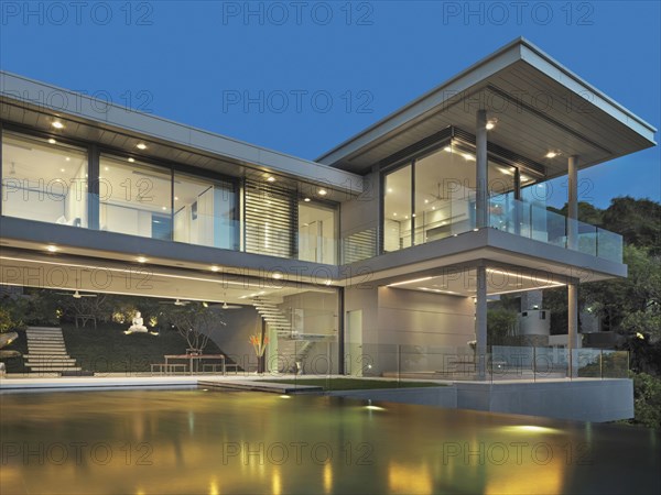 Multiple story modern home with swimming pool at dusk