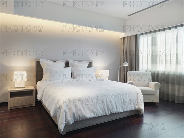 Master bedroom with white bedding and armchair