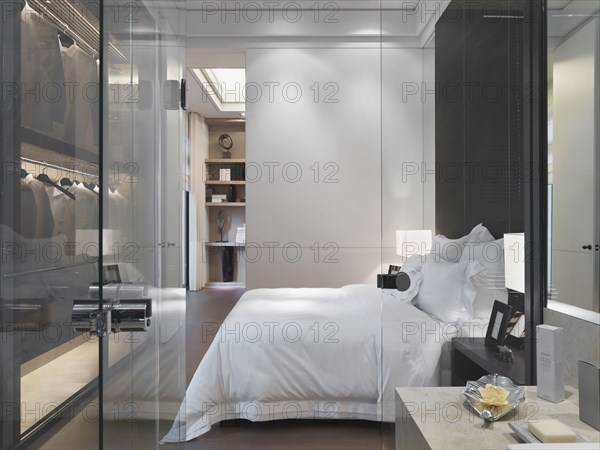 Glass door and wall separating modern bedroom from bathroom