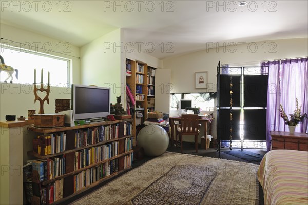 Study table and television with cropped bed in spacious bedroom at house