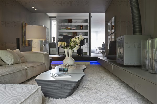 Large living room with rug on floor and view of piano in background