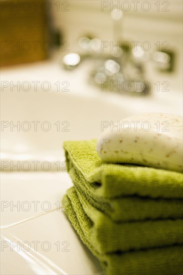 Stack of Green Towels with Soap on Bathroom Counter