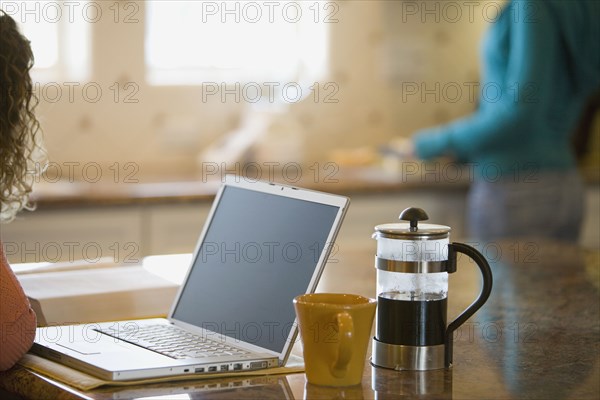 Young woman drinking coffee and working on her laptop in the morning