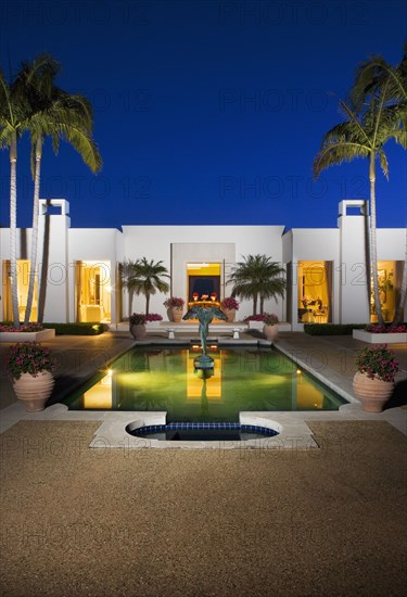 Evening exterior of a large white modern house with a swimming pool