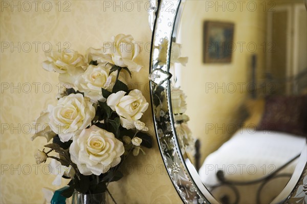 Detail of with white roses next to antique vanity mirror.