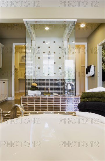 Image of bathtub and towels with shower in background.