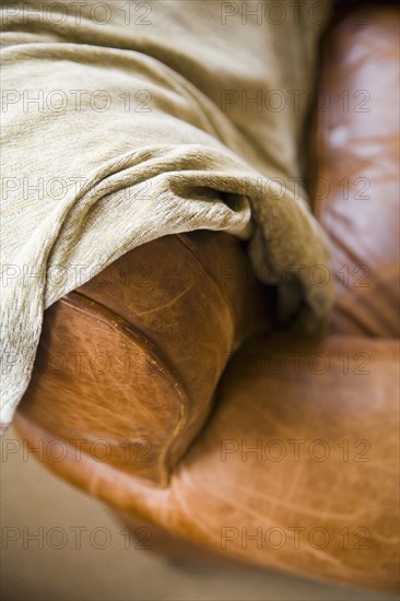 Detail of leather couch arm with throw blanket.