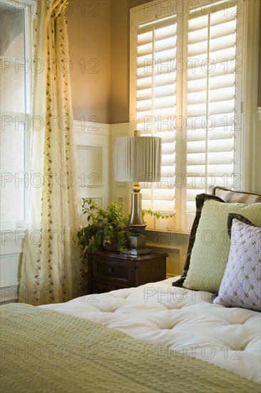 Purple and green decorative pillows on bed near window